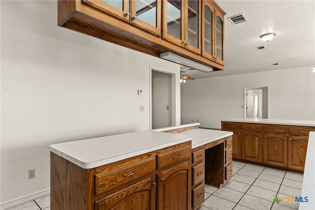 kitchen featuring light tile patterned floors, a textured ceiling, a center island, and ceiling fan