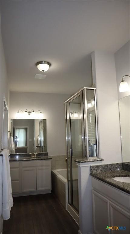 327 Limestone Crk, New Braunfels, TX 78130 - bathroom featuring two vanities, a garden tub, a shower stall, and wood finished floors