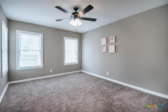 carpeted spare room featuring baseboards and ceiling fan