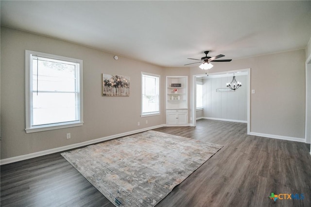 interior space featuring baseboards, dark wood finished floors, and ceiling fan with notable chandelier