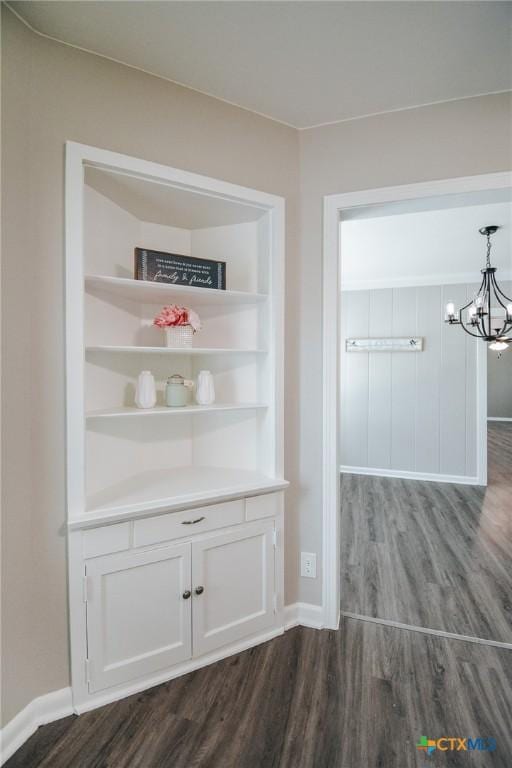 interior details with baseboards, an inviting chandelier, and wood finished floors