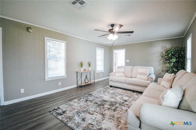 living area with visible vents, ornamental molding, dark wood-style floors, baseboards, and ceiling fan