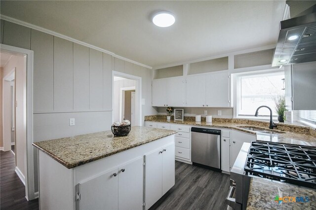 kitchen featuring a sink, a kitchen island, appliances with stainless steel finishes, light stone countertops, and dark wood-style flooring