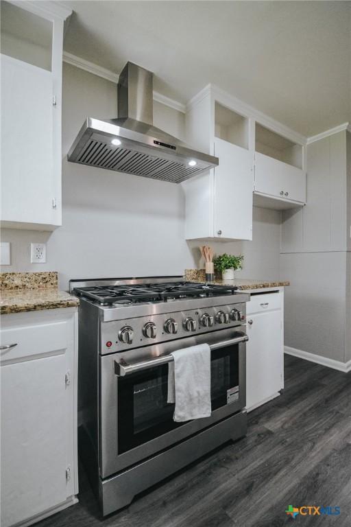 kitchen with light stone counters, dark wood-style floors, white cabinetry, high end stainless steel range oven, and wall chimney exhaust hood