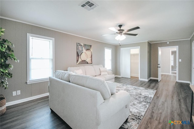 living room with a ceiling fan, baseboards, wood finished floors, visible vents, and ornamental molding