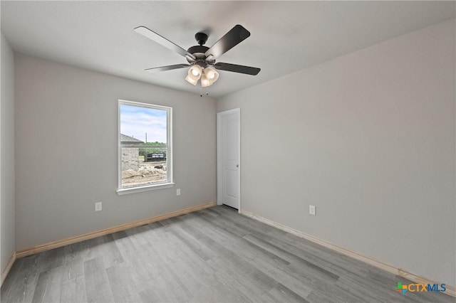spare room with baseboards, wood finished floors, and a ceiling fan