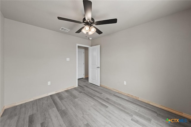 empty room with wood finished floors, visible vents, a ceiling fan, and baseboards