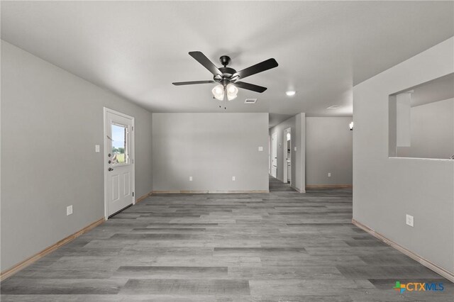 unfurnished living room with wood finished floors, ceiling fan, and baseboards