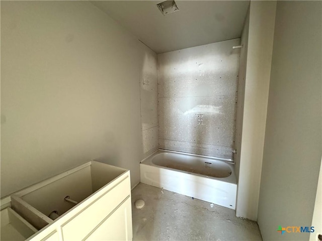 bathroom with concrete flooring and a bathing tub