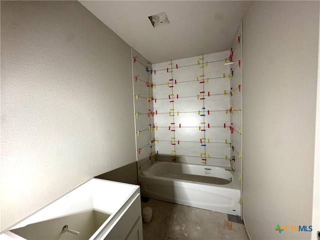 bathroom featuring concrete flooring, vanity, and bathing tub / shower combination