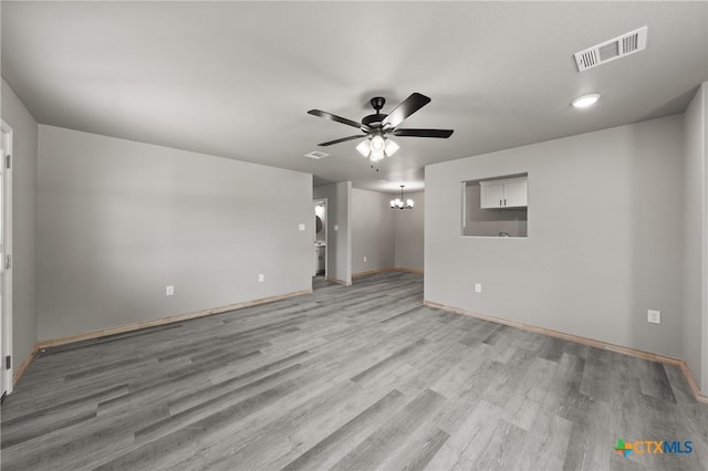 unfurnished room with visible vents, recessed lighting, ceiling fan with notable chandelier, baseboards, and light wood-type flooring