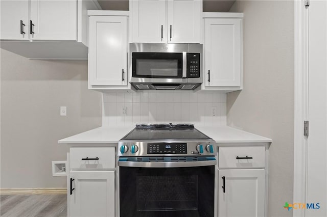 kitchen featuring appliances with stainless steel finishes, white cabinetry, light countertops, and backsplash