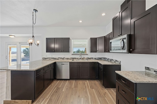 kitchen with sink, light hardwood / wood-style flooring, appliances with stainless steel finishes, hanging light fixtures, and kitchen peninsula