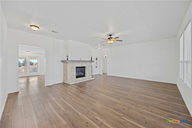 unfurnished living room featuring light hardwood / wood-style flooring, a fireplace, and ceiling fan