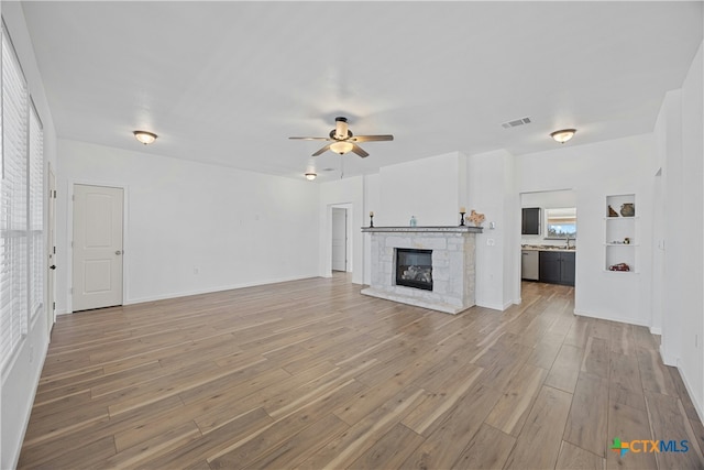 unfurnished living room featuring a fireplace, light hardwood / wood-style floors, and ceiling fan