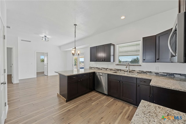 kitchen with pendant lighting, sink, dark brown cabinetry, stainless steel appliances, and light hardwood / wood-style flooring