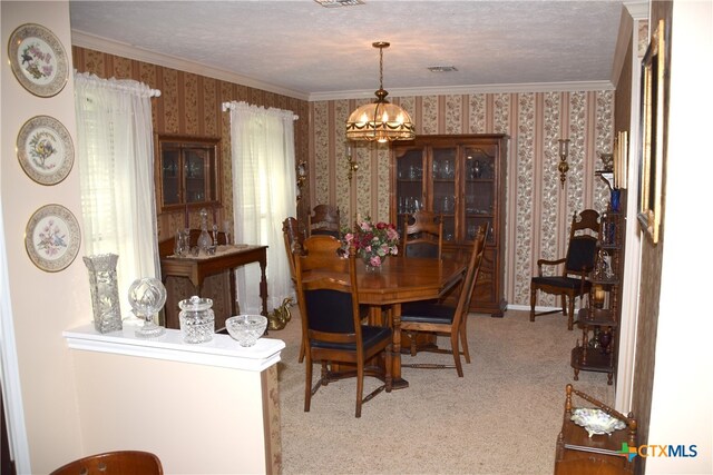 dining room featuring ornamental molding, carpet flooring, a textured ceiling, and a notable chandelier