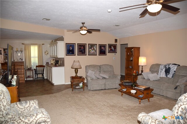 living room featuring ceiling fan, a textured ceiling, and lofted ceiling