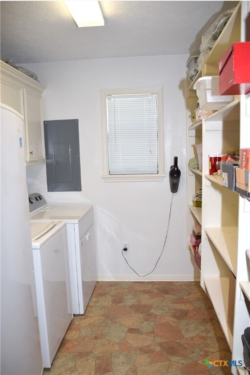 washroom with electric panel, cabinets, and independent washer and dryer