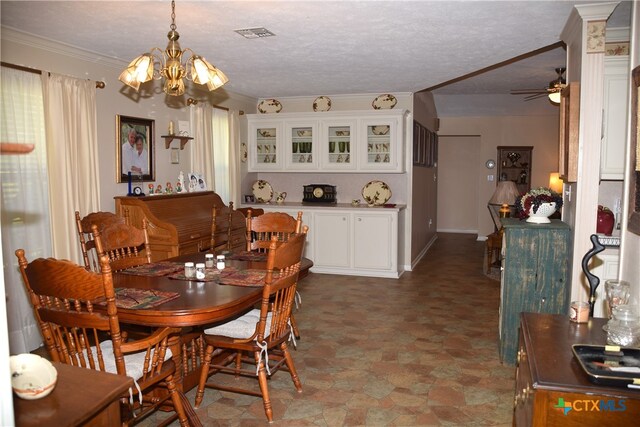 dining space with ornamental molding, ceiling fan with notable chandelier, and a textured ceiling