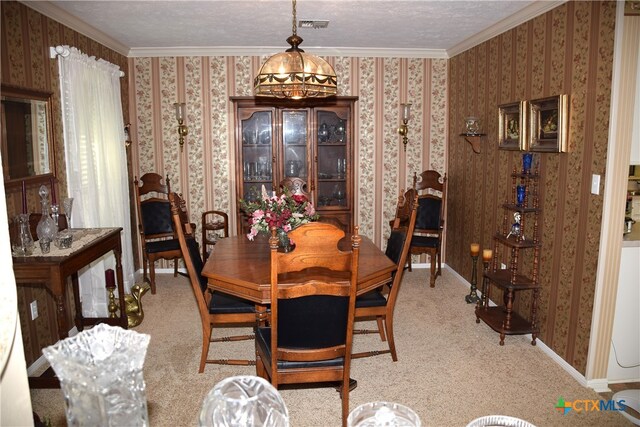 dining room featuring ornamental molding, light colored carpet, and a textured ceiling