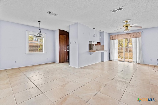 unfurnished living room with a wealth of natural light, light tile patterned floors, ceiling fan, and a textured ceiling