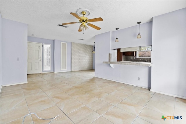 unfurnished living room with ceiling fan, light tile patterned floors, plenty of natural light, and brick wall