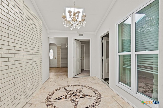 hallway featuring light tile patterned floors, crown molding, brick wall, and a chandelier