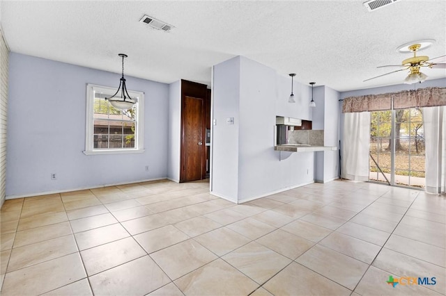 interior space featuring ceiling fan, light tile patterned flooring, and a textured ceiling