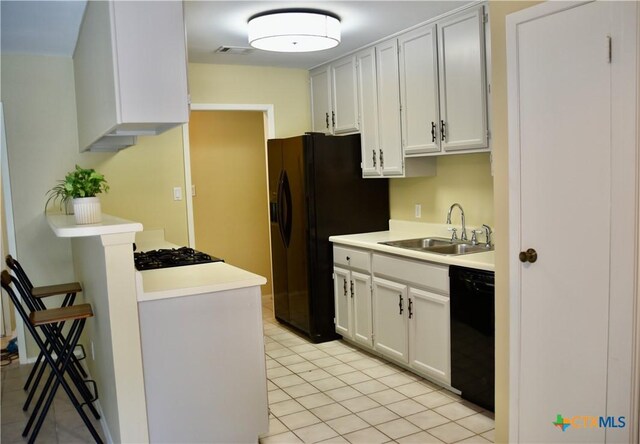 2007 Castle Gate Cir, San Marcos, TX 78666 - kitchen with black appliances, light tile patterned floors, light countertops, and a breakfast bar area