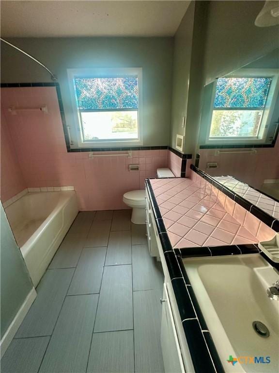 bathroom featuring tile patterned floors, vanity, tile walls, and toilet