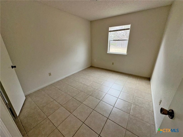 unfurnished room featuring baseboards, a textured ceiling, and light tile patterned flooring