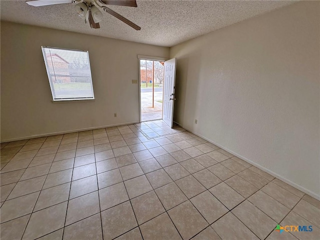 empty room with ceiling fan, a textured ceiling, baseboards, and light tile patterned floors