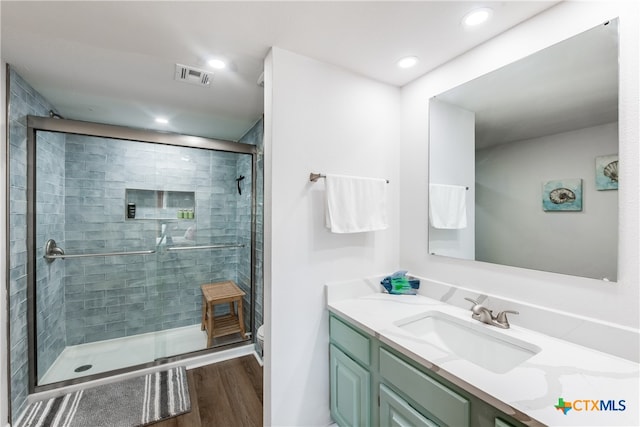 bathroom featuring toilet, vanity, hardwood / wood-style flooring, and a shower with door