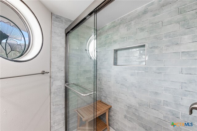 bathroom with a wealth of natural light and a shower with shower door