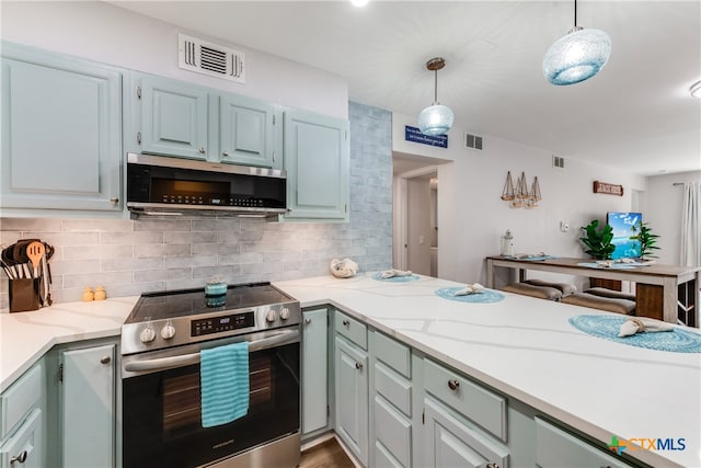 kitchen featuring stainless steel appliances, light stone countertops, hanging light fixtures, hardwood / wood-style floors, and decorative backsplash