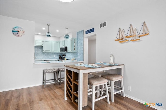 5973 State Highway 361 Unit 125, Port Aransas, TX 78373 - kitchen featuring black microwave, tasteful backsplash, light wood-style floors, light countertops, and pendant lighting