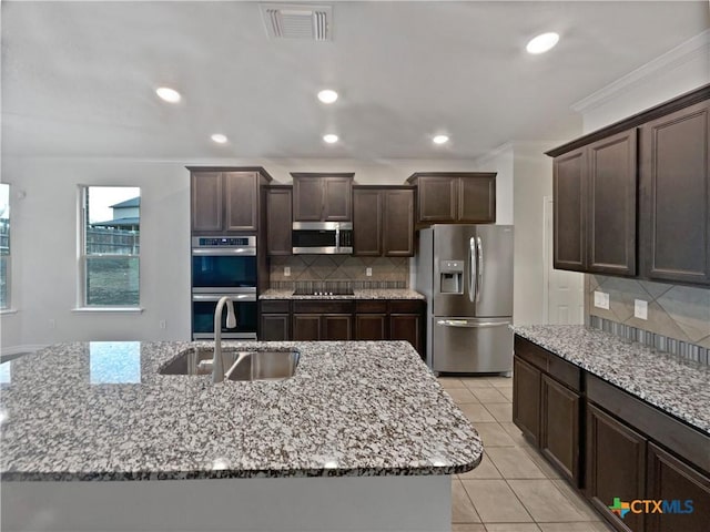 kitchen with decorative backsplash, appliances with stainless steel finishes, crown molding, sink, and a center island with sink