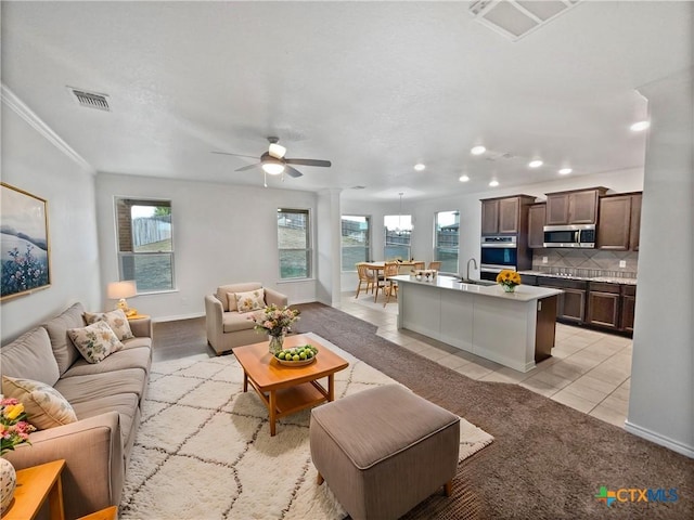 living room featuring light tile patterned floors, a wealth of natural light, crown molding, and ceiling fan