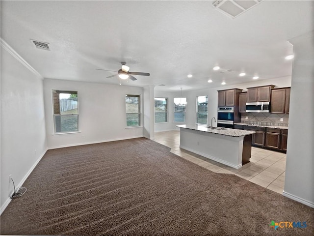 kitchen with light colored carpet, stainless steel appliances, a wealth of natural light, and tasteful backsplash