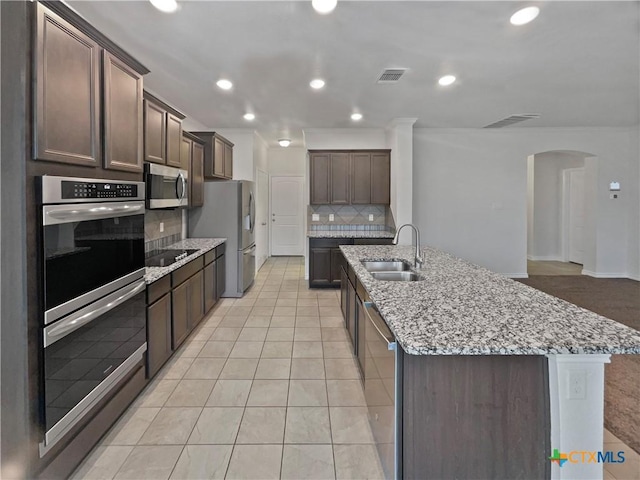 kitchen featuring backsplash, dark brown cabinetry, sink, and appliances with stainless steel finishes