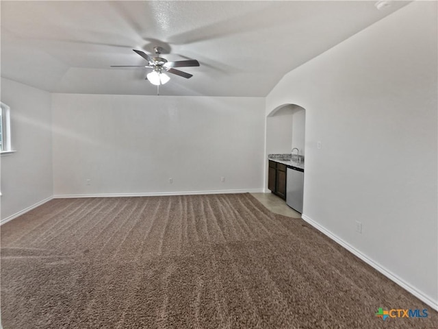 unfurnished living room featuring ceiling fan, sink, carpet floors, and lofted ceiling