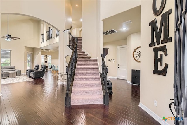 foyer with ceiling fan, dark wood-type flooring, and a high ceiling