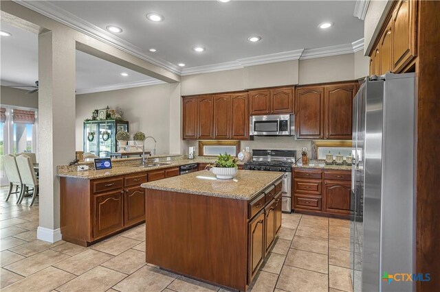3 Sago Dr, Port Lavaca, TX 77979 - kitchen featuring appliances with stainless steel finishes, a sink, a center island, ornamental molding, and light stone countertops