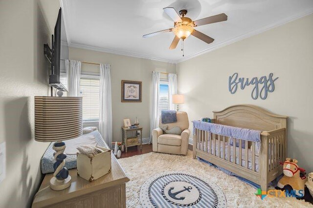 3 Sago Dr, Port Lavaca, TX 77979 - bedroom featuring crown molding, a crib, ceiling fan, baseboards, and wood finished floors