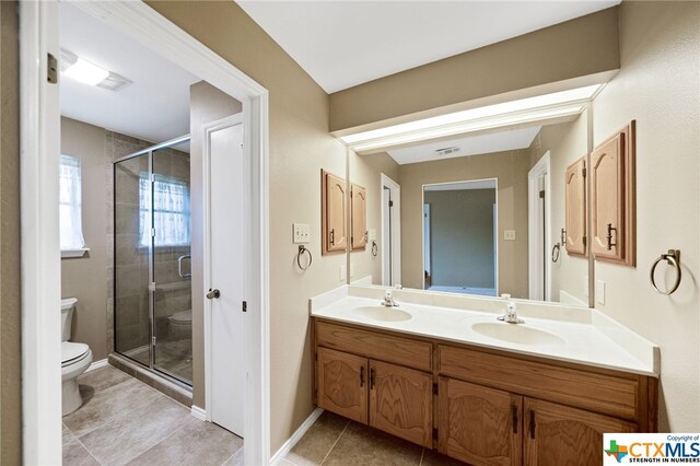 bathroom featuring toilet, tile patterned floors, vanity, and a shower with door