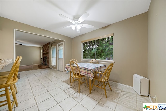 tiled dining area with a fireplace, ceiling fan, and radiator