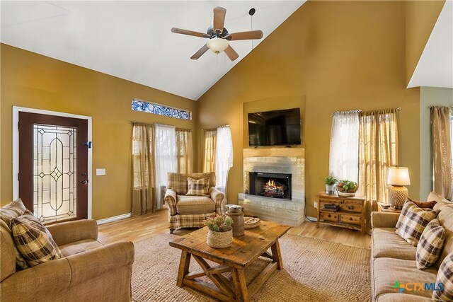 living room featuring a fireplace, ceiling fan, light hardwood / wood-style flooring, and high vaulted ceiling