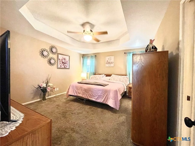 bedroom with a tray ceiling, carpet, baseboards, and ceiling fan