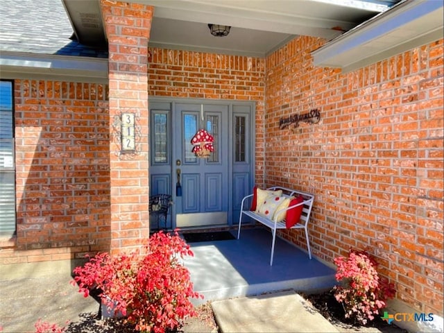 doorway to property featuring brick siding